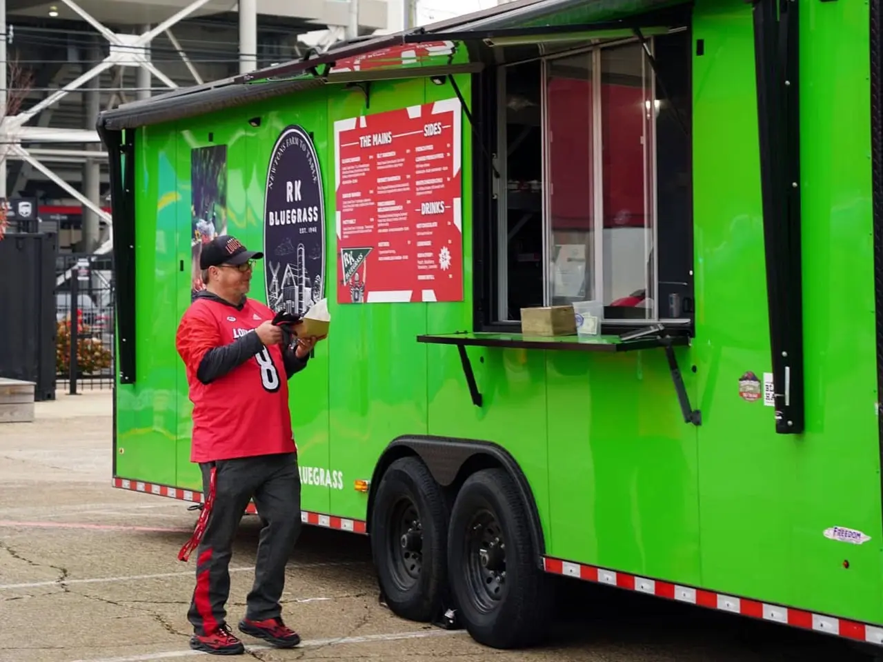 Newton’s Farm-to-Table food truck serving a sports fan near a university stadium in Kentucky.