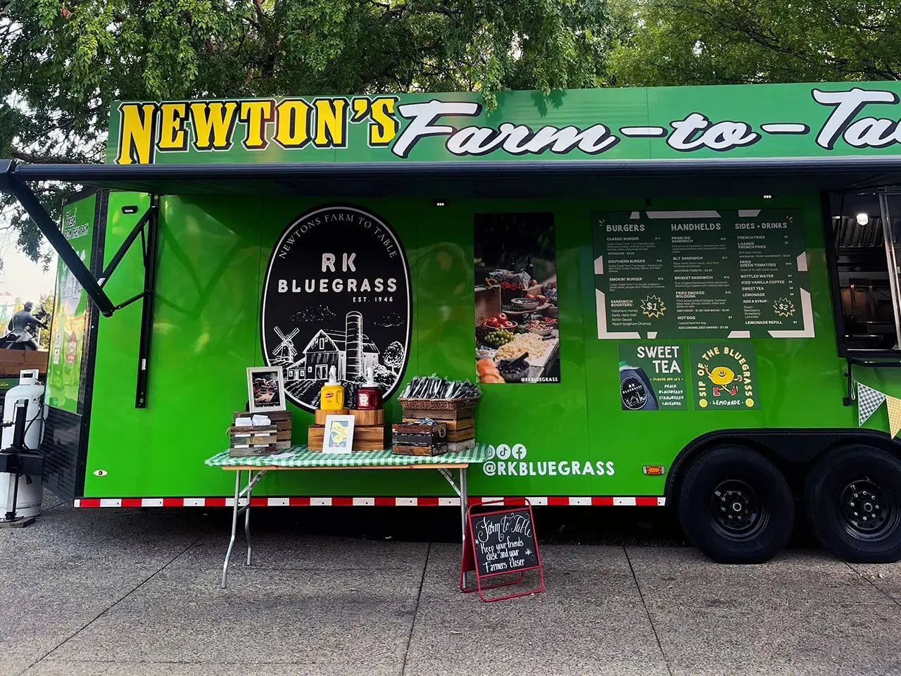 Bright green food truck featuring local Kentucky fare, parked at an event with utensils and condiments on a side table.
