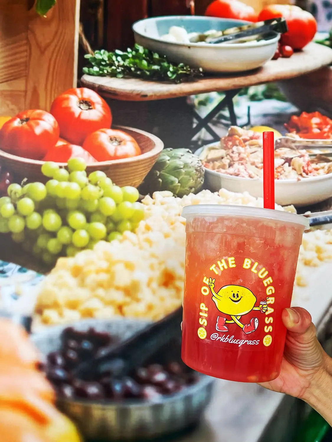 Farm-to-table display with fresh vegetables and a fruity drink from RK Bluegrass in the foreground.
